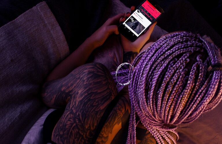Person with purple hair in braids surfing the web on their phone