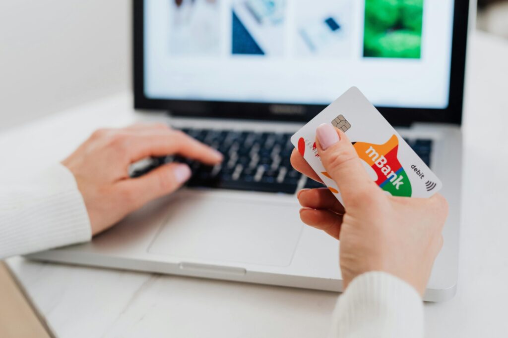 Close-up shot of a person using a laptop while holding a credit card.
