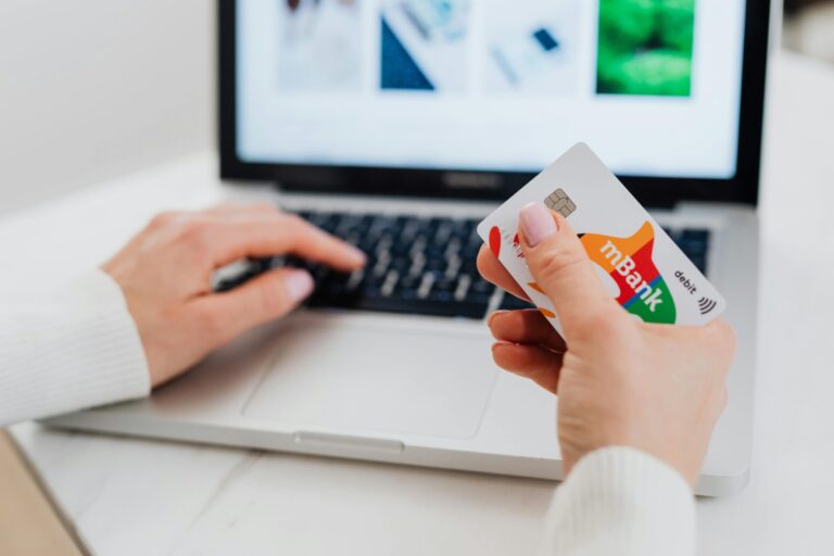 Close-up shot of a person using a laptop while holding a credit card.