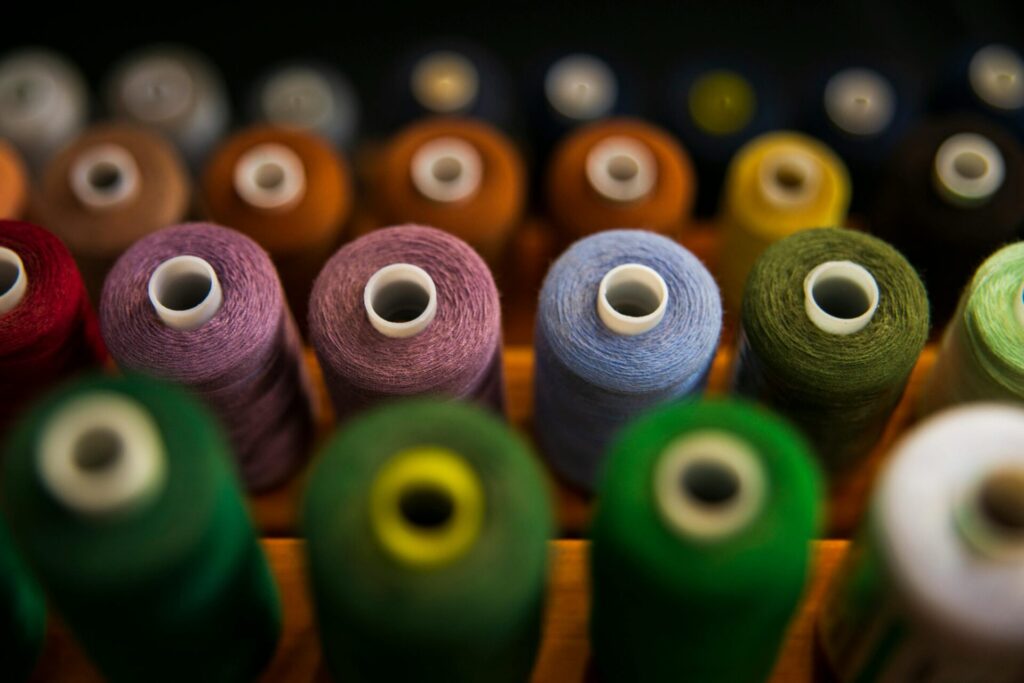 A colorful photo showing multiple spools of fiber thread on a wooden holder